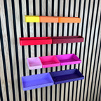 Organizer Boxen für Akustikpaneele in Gelb, Orange, Rot, Pink und Lila an einer Holz-Lamellenwand