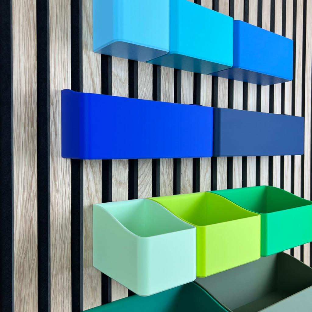 Detailansicht hoher Organizer Boxen in Blau und Grün am Holz-Akustikpaneel