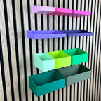 Organizer Boxen in Pastell- und Grüntönen schräg an der Holz-Lamellenwand