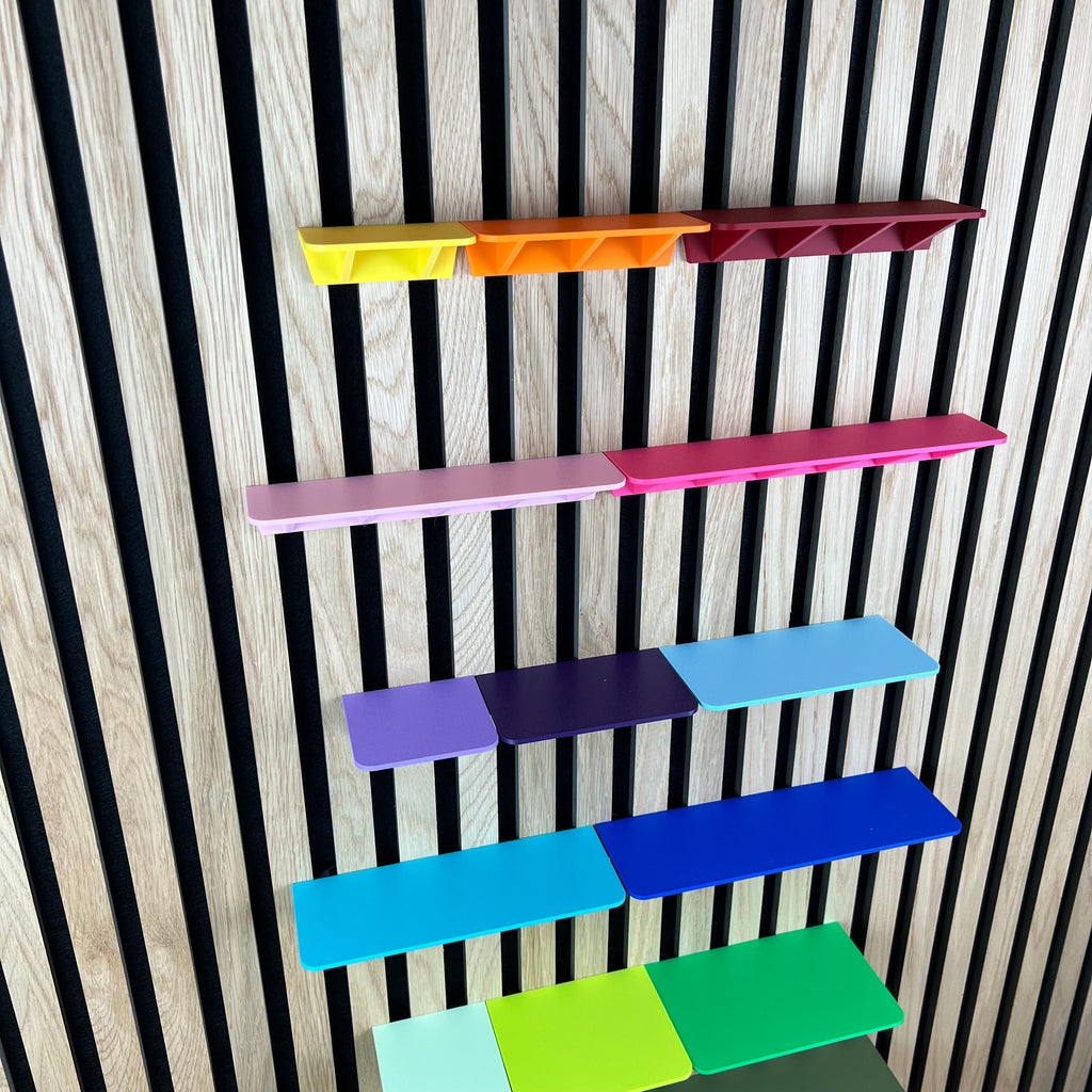 Ablagen für Akustikpaneele in vielen Farben an einer Holz-Lamellenwand