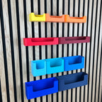 Organizer Box mit Eingriff für Akustikpaneele in Gelb, Orange, Rot und Blau an der Lamellenwand