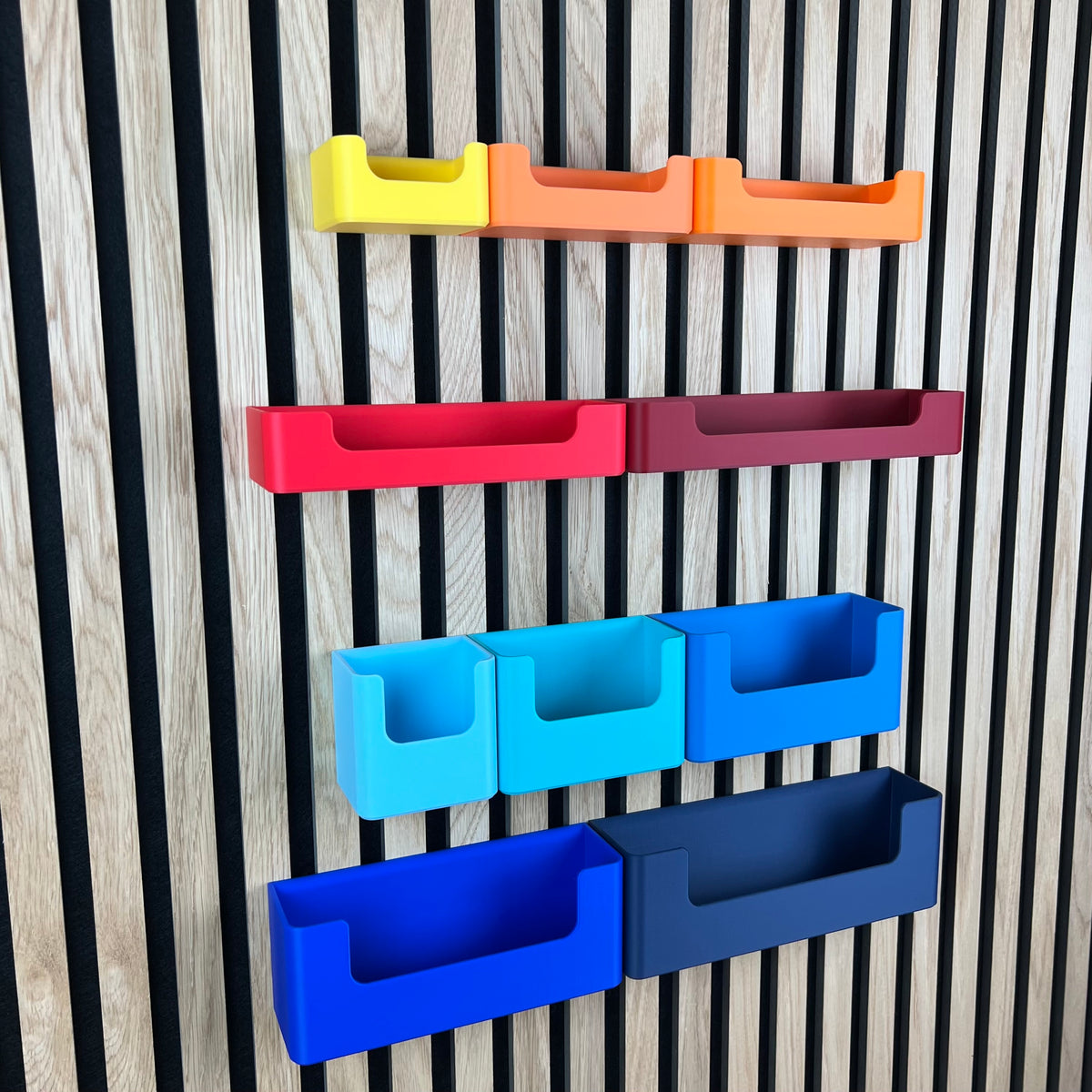 Organizer Box mit Eingriff für Akustikpaneele in Gelb, Orange, Rot und Blau an der Lamellenwand