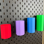 Vier achteckige Boxen in Rot, Lila, Blau und Grün an schwarzer SKÅDIS Lochwand, Schrägansicht