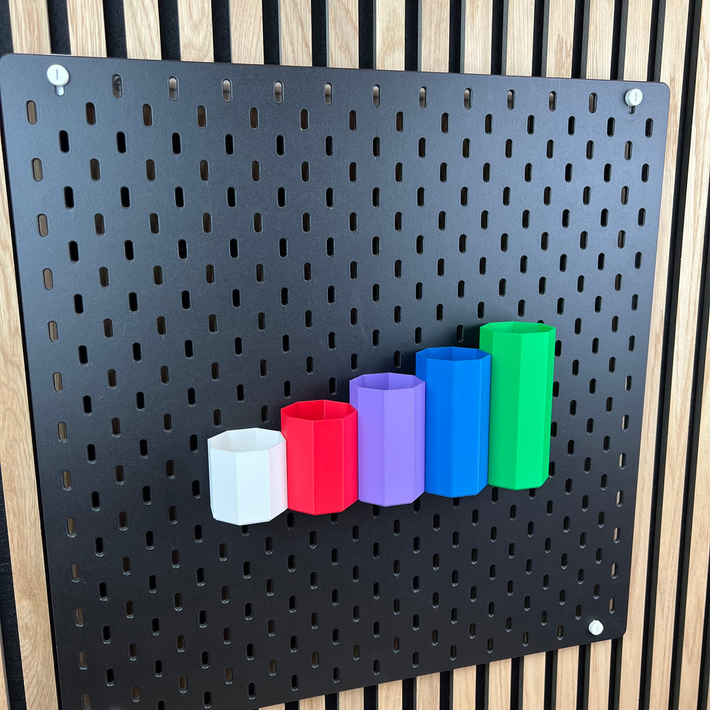 Schwarze Lochwand mit achteckigen Boxen in Weiß, Rot, Lila, Blau und Grün, seitliche Perspektive