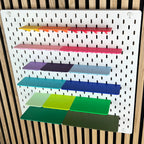 Farbige Ablagen für die IKEA SKÅDIS Lochwand, leicht seitliche Ansicht der sechs Regalreihen