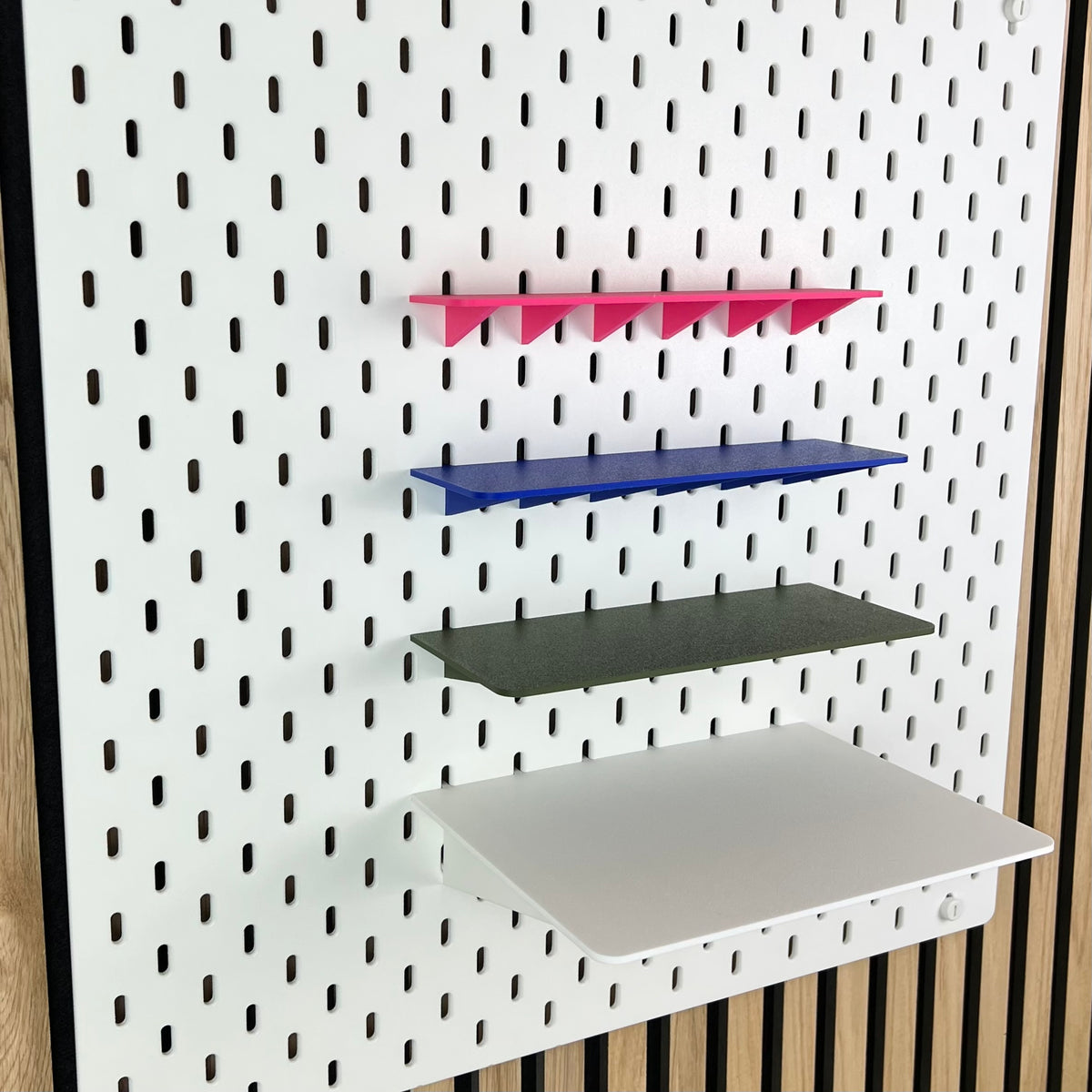 Vier SKÅDIS Ablagen in Pink, Blau, Oliv und Weiß mit zunehmender Tiefe an der Lochwand