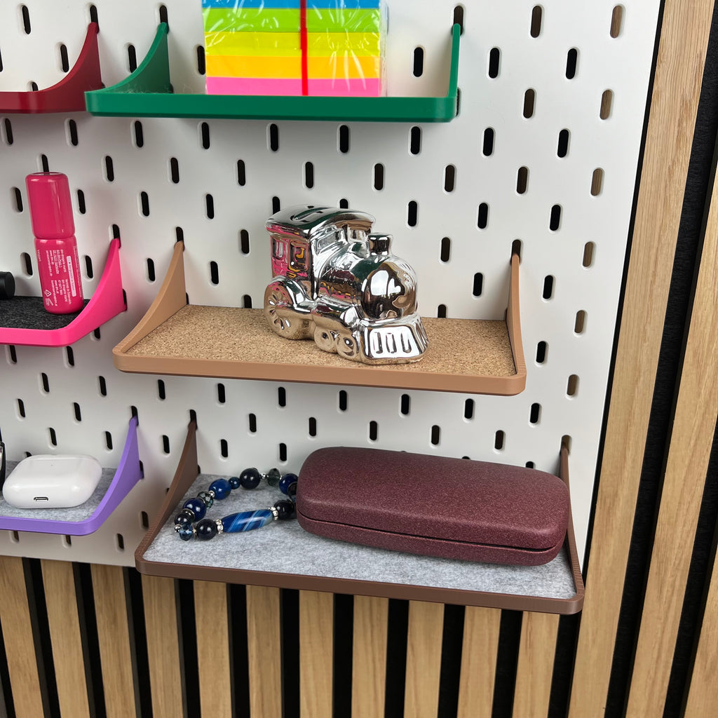 SKÅDIS Ablagen mit Rand halten Sparschwein, Perlenkette, Etui und AirPods an weißer Lochwand