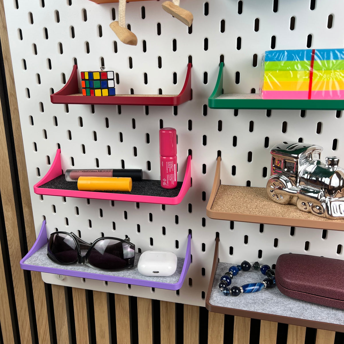 Weiße SKÅDIS Lochwand mit Ablagen voller Sonnenbrille, Kosmetik, Zauberwürfel und Sparschwein