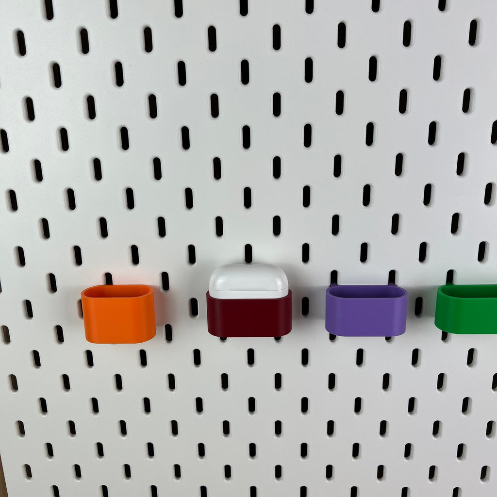 Detailaufnahme von AirPods-Halterungen an weißer Lochwand, AirPods Pro im dunkelroten Halter