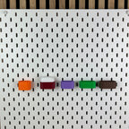 Fünf AirPods-Halterungen an weißer IKEA SKÅDIS Lochwand, Frontalansicht mit AirPods Pro