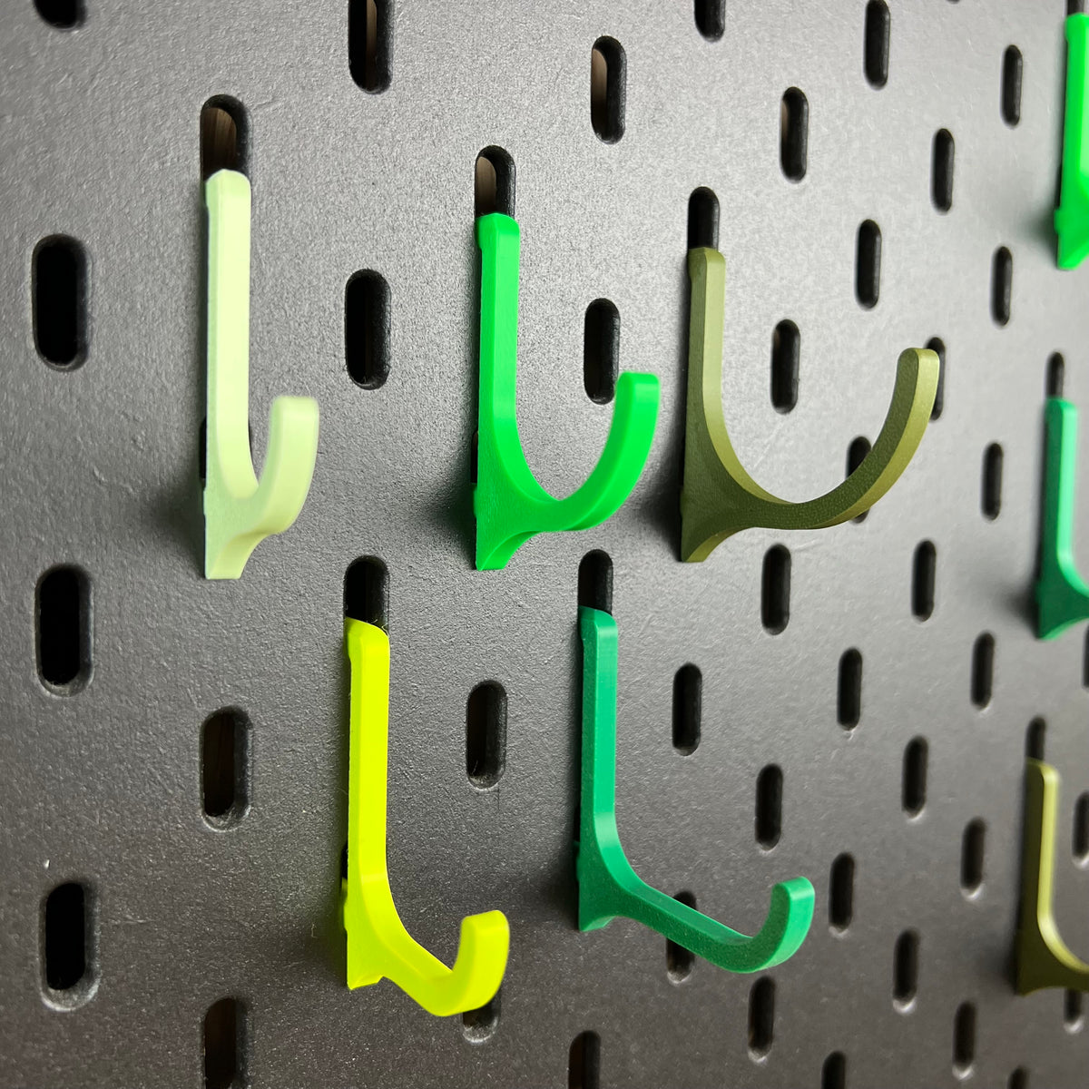 Grüne SKÅDIS Haken in Mint Grün, Bambus Grün und Olive Grün im Detail an der schwarzen Lochwand