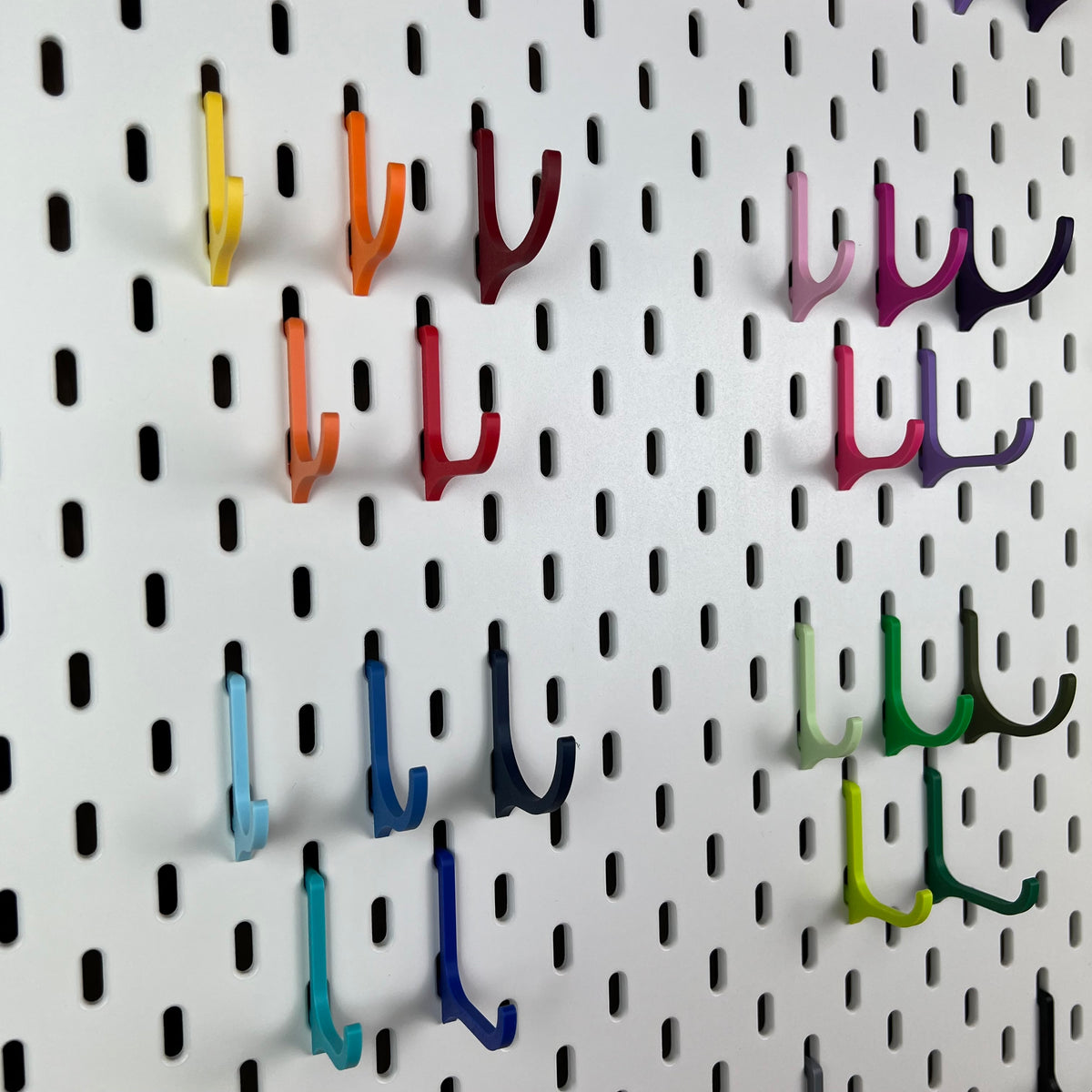 Detailansicht von SKÅDIS Haken in Gelb, Rot, Violett, Blau und Grün an weißer Lochwand