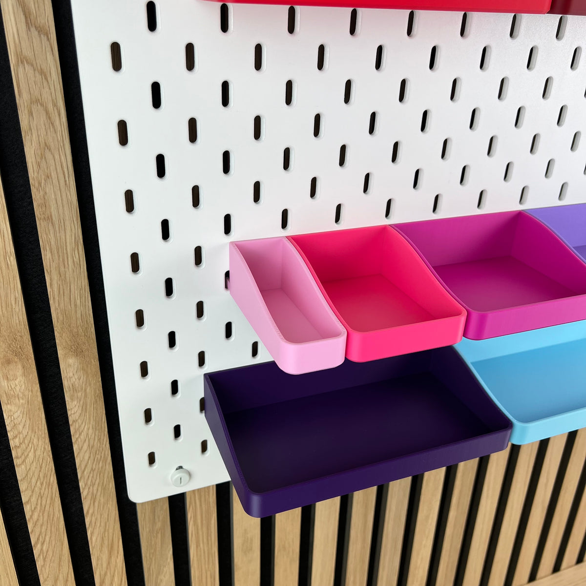 Pinke, magenta und violette SKÅDIS Boxen an der Lochwand, Blick von schräg unten in die Boxen