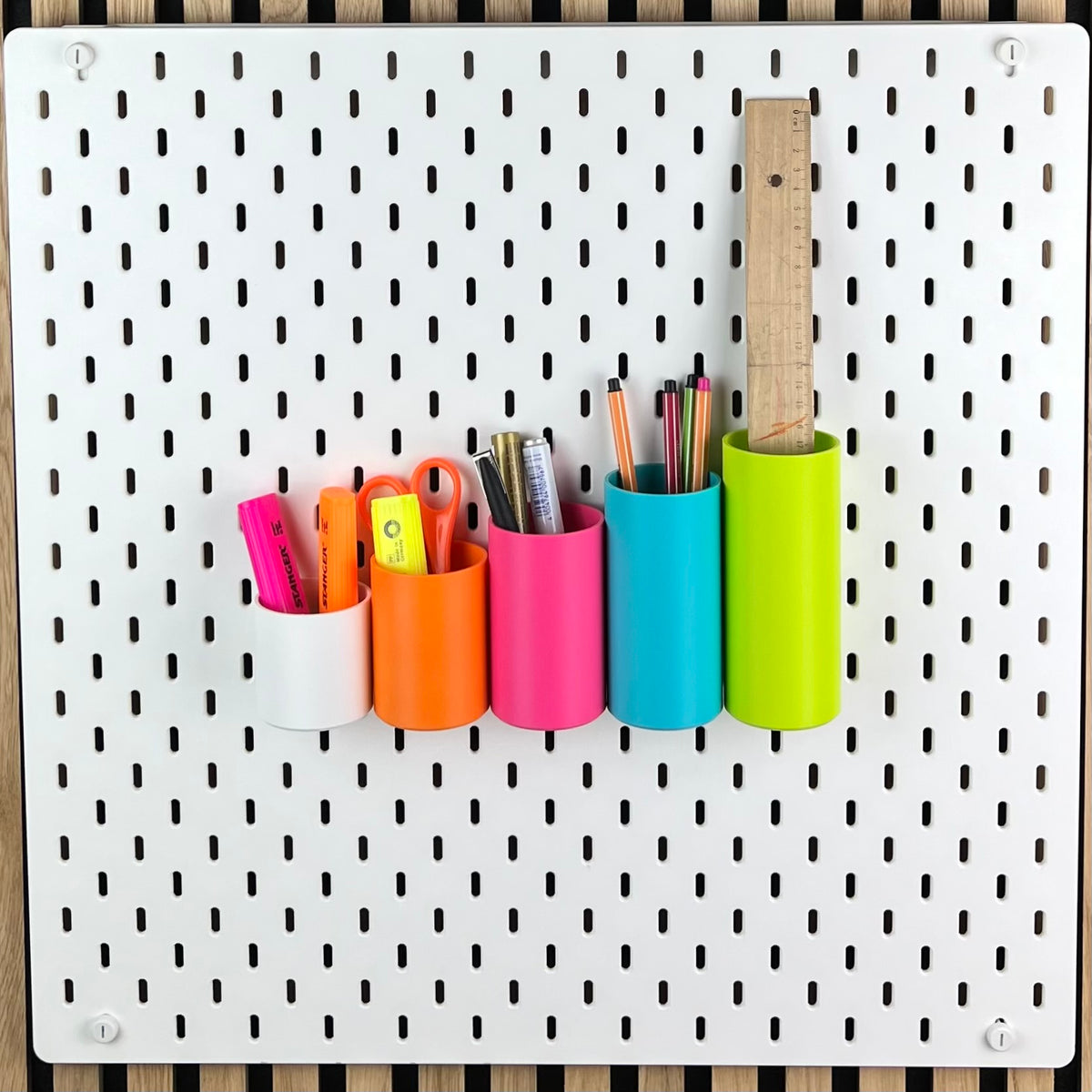 Fünf runde SKÅDIS Boxen in Weiß, Orange, Pink, Blau und Grün als Stiftehalter an weißer Lochwand
