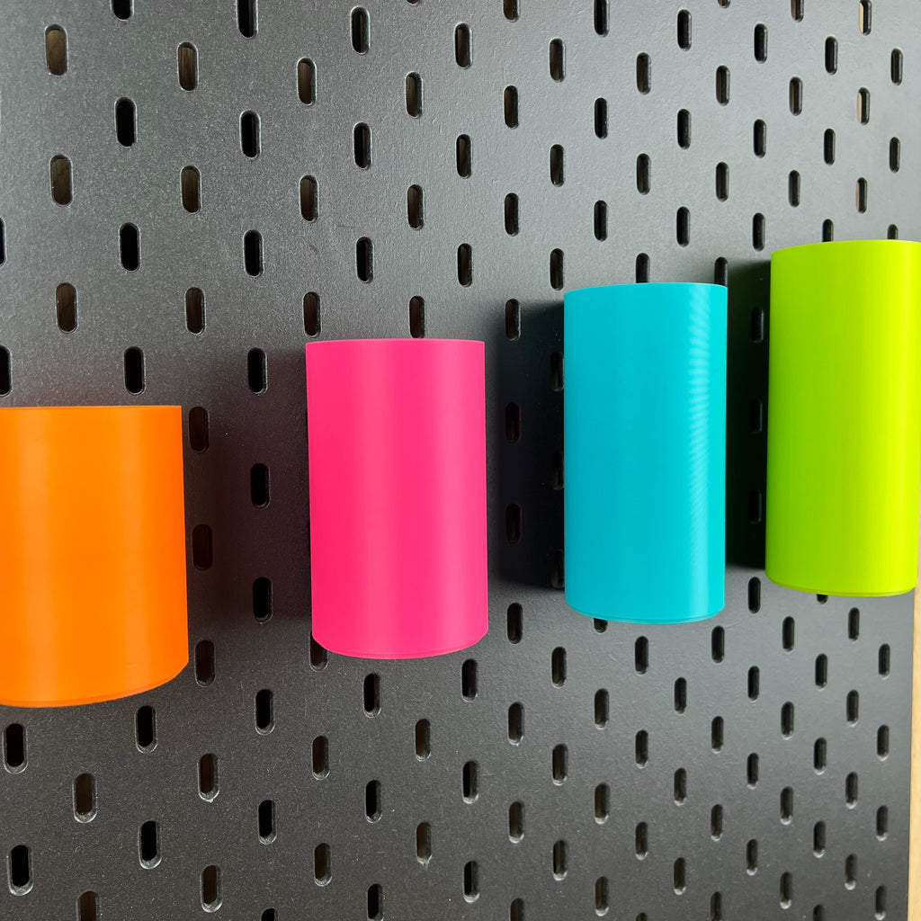 Detailaufnahme runder SKÅDIS Boxen in Orange, Pink, Blau und Grün an schwarzer Lochwand