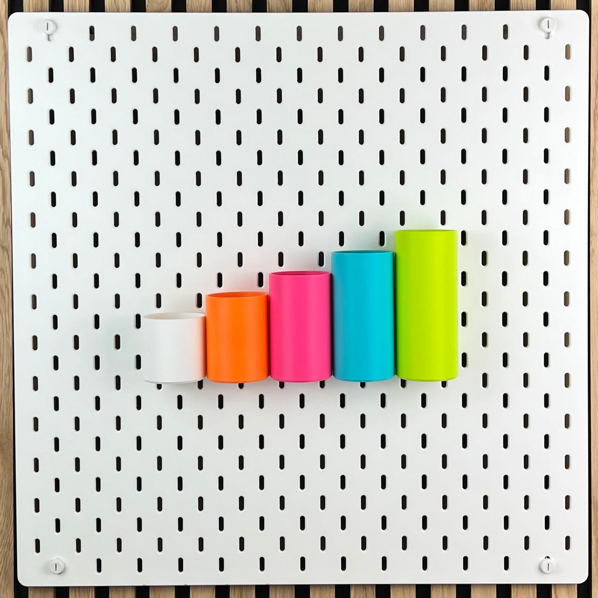 Weiße IKEA SKÅDIS Lochwand mit fünf runden Boxen vor Akustikpaneel aus Holz, Gesamtansicht