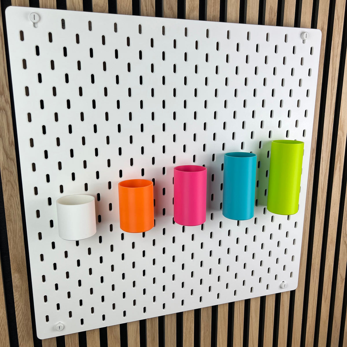 Runde Boxen an weißer IKEA SKÅDIS Lochwand, leicht seitliche Ansicht der fünf Farben