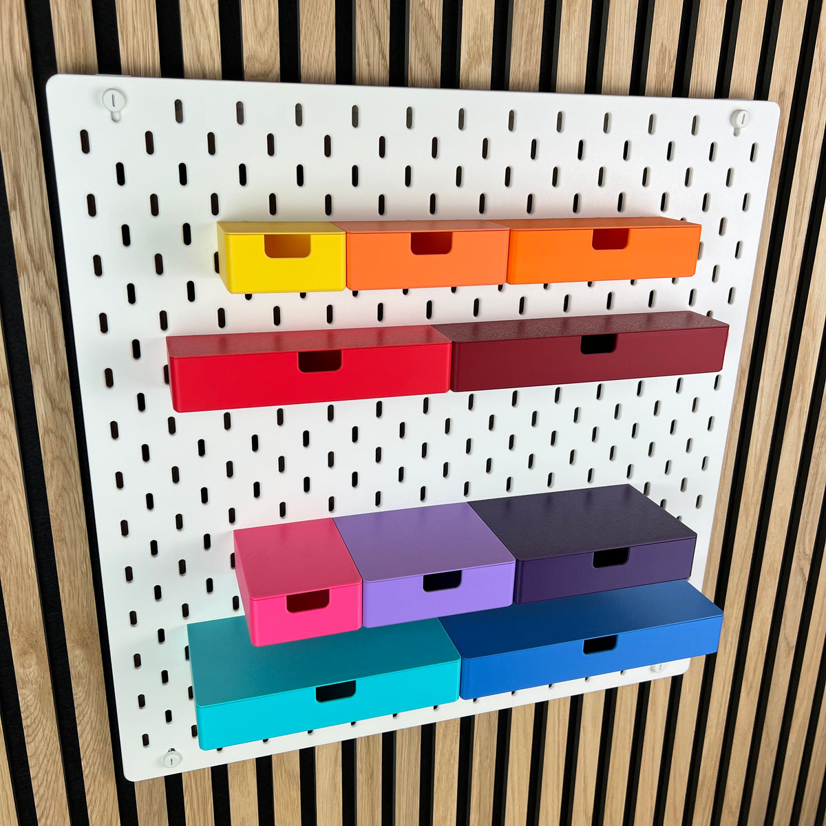 Weiße IKEA SKÅDIS Lochwand mit bunten 3D-gedruckten Schubladen mit Eingriffsloch in mehreren Größen