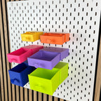 Sechs geöffnete SKÅDIS Schubladen in Regenbogenfarben zeigen unterschiedliche Innentiefen