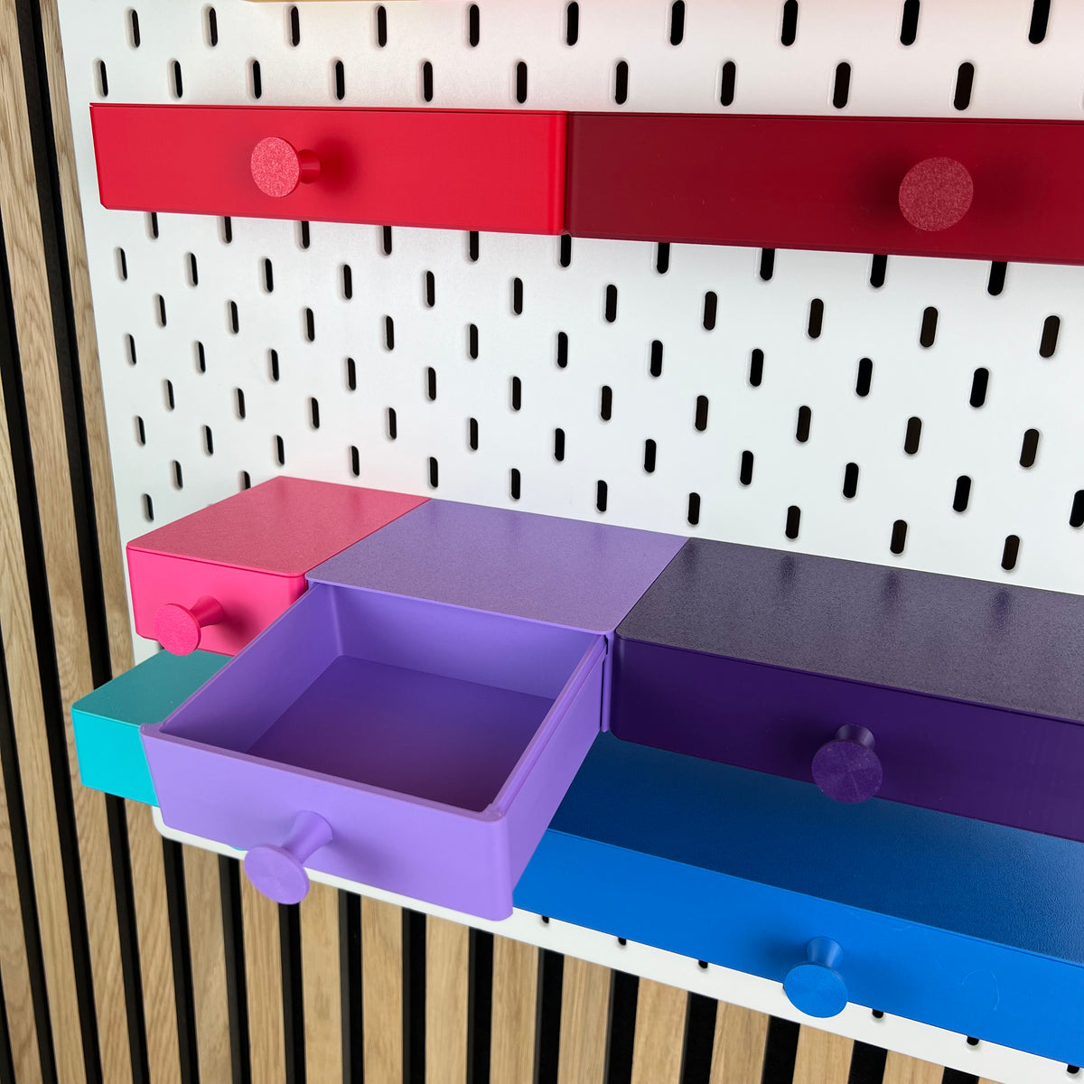 Geöffnete violette SKÅDIS Schublade zeigt den Innenraum, umgeben von geschlossenen Schubladen