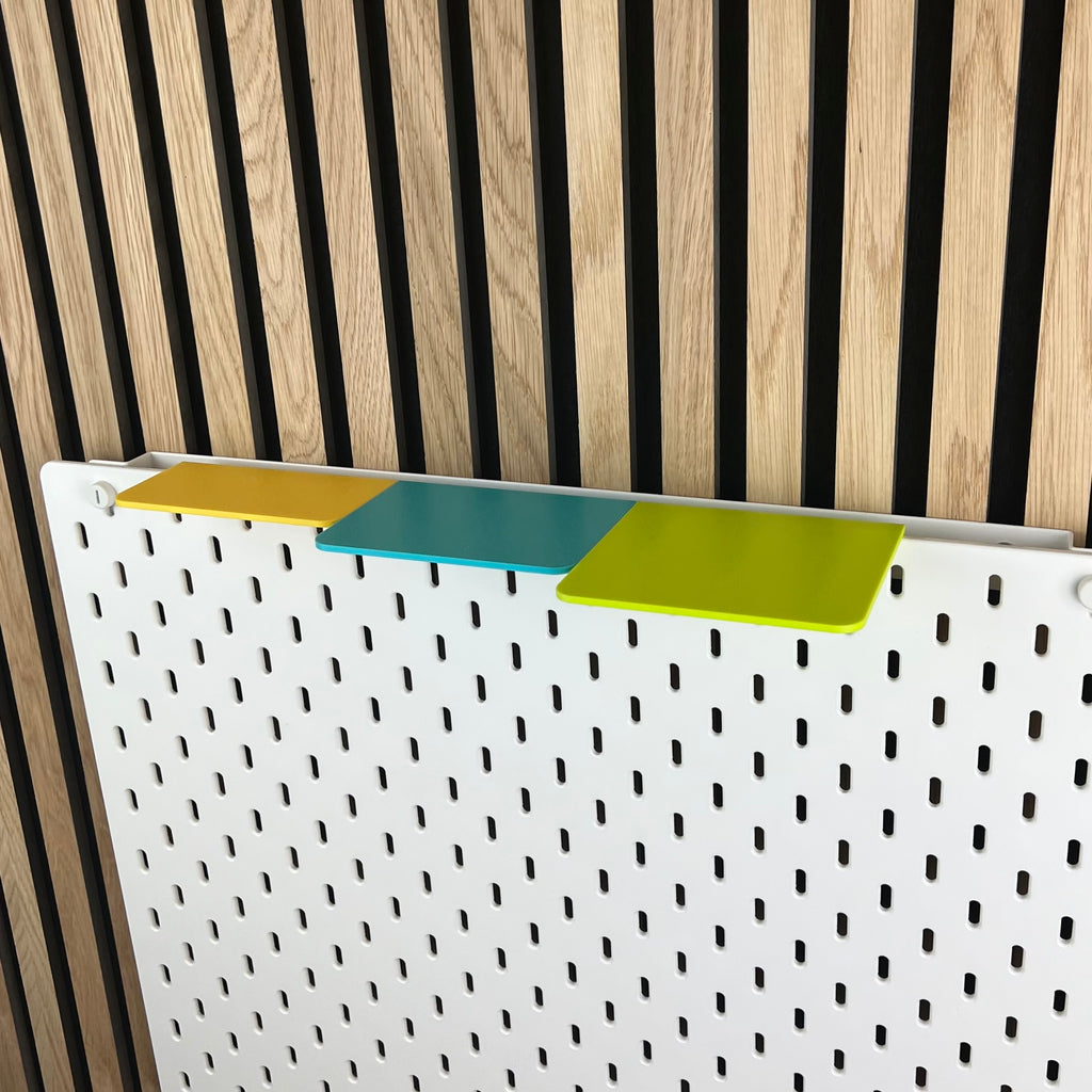 Drei TOP-Ablagen auf der Oberkante einer weißen IKEA SKÅDIS Lochwand vor Holzwand